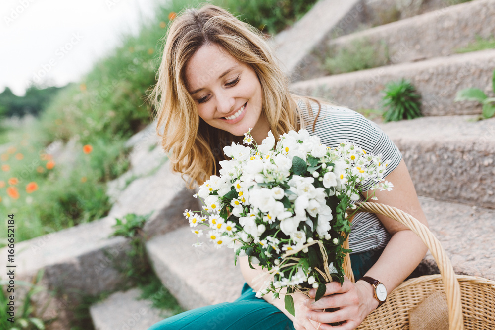 Blonde woman in the nature holding a bunch of flowers Blonde woman in the nature holding a bunch of flowers