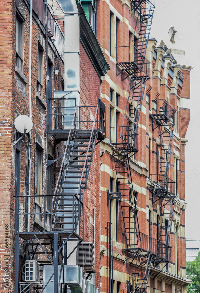 black metal fire escape stairs and steps along old brick apartment building  in Montreal Stock Photo