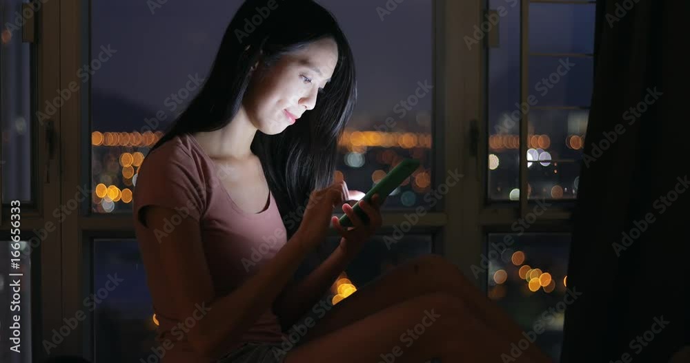 Woman using cellphone at night in home