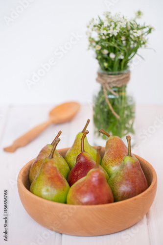 Pears in a wooden plate with white flowers on a light background