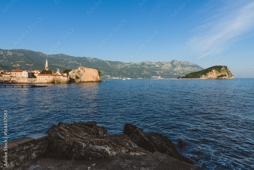 Budva Old town, St.John church spire, mountains, St. Nicholas island and Adriatic sea panoramic landscape. Tourist capital Budva wide angle view by golden hour.