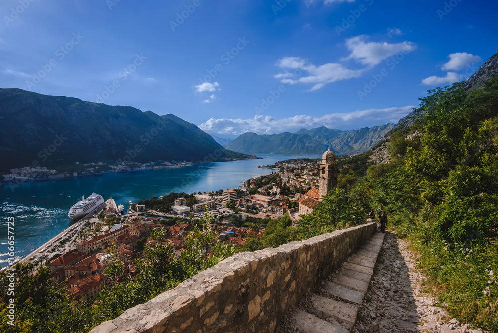 Kotor Bay and Old Town view from above Kotor's castle of San Giovanni. Stone staircase on Kotor fortress, traditional house roofs, cathedral dome and Boka Kotorska wide angle view. Montenegro.