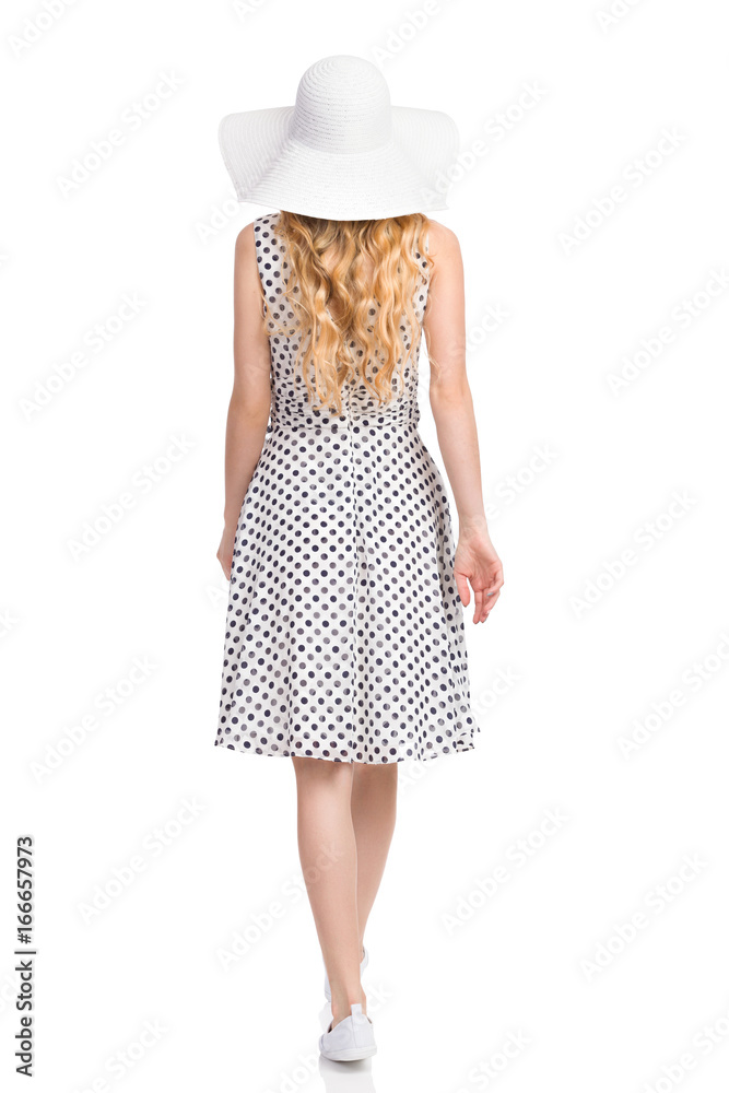 Rear View Of Walking Woman In White Dotted Dress, Sun Hat And Sneakers Rear View Of Walking Woman In White Dotted Dress, Sun Hat And Sneakers