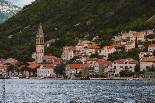 Famous ancient Perast village on Kotor bay by cloudy day in Montenegro. View to Perast Old Town roofs and mountains from water of Boka Kotorska. Postcard montenegrin landscape.