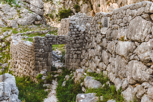 Ancient ruins and mountain valley landscape near Kotor castle in Montenegro. Old stone wall of ruined city in Kotor Bay region near hike path to Lovchen mountain. photo