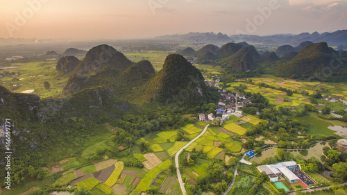 Photography Aerial view of a village surrounded by Padi fields and hills in Guanxi, China