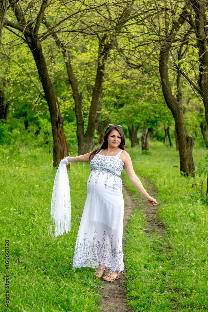 Pregnant woman in white dress in the forest