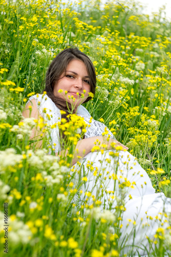 Pregnant woman lies in a field of flowers