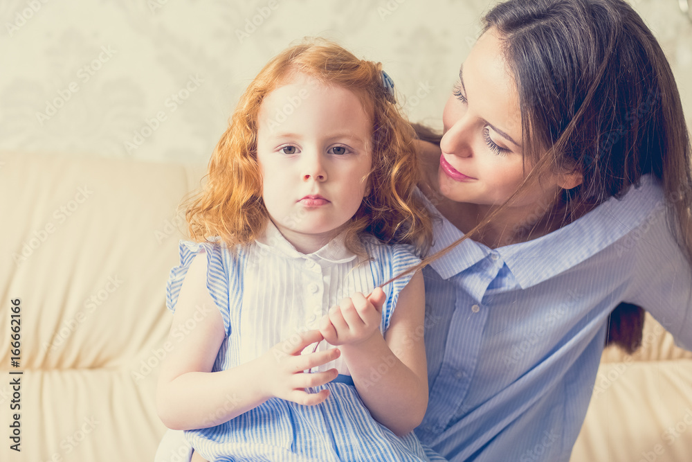 Φωτογραφία Serious little girl playing with mothers hair lock