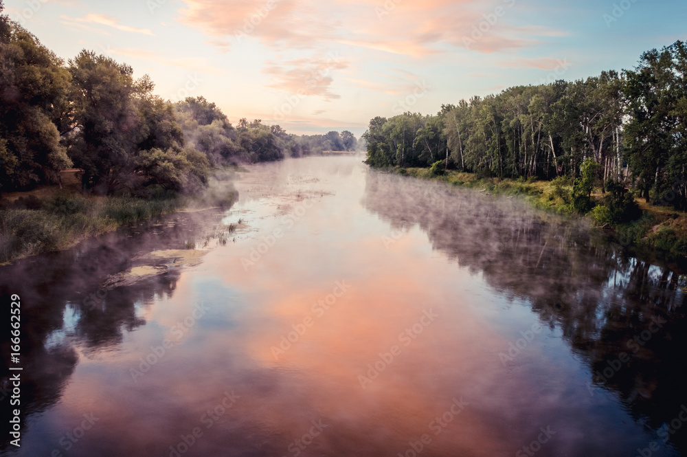 Magnificent sunrise on the river in the summer with fog over the water