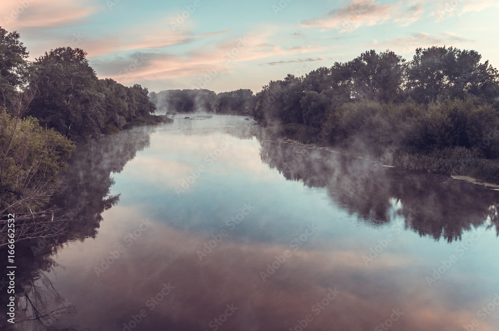 Magnificent sunrise on the river in the summer with fog over the water