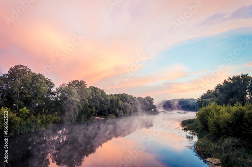 Magnificent sunrise on the river in the summer with fog over the water © bearok