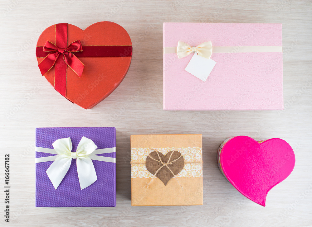 plenty assorted colorful and different in the shape and size gift boxes on light wooden background for the celebration of different holidays, flat lay