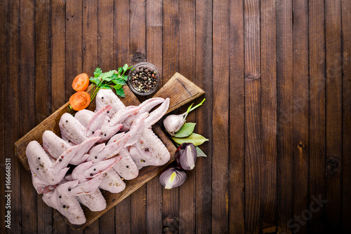 Raw chicken wings with spices. On Wooden surface. Top view.