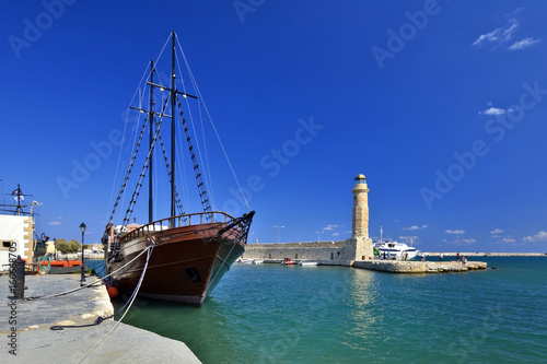 Lighthouse and beautiful  old-style wooden ship  at the  venetian harbor of Rethymno, Crete, Greece