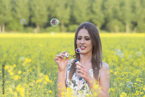 Yong girl play with soap bubbles in the middle of the field