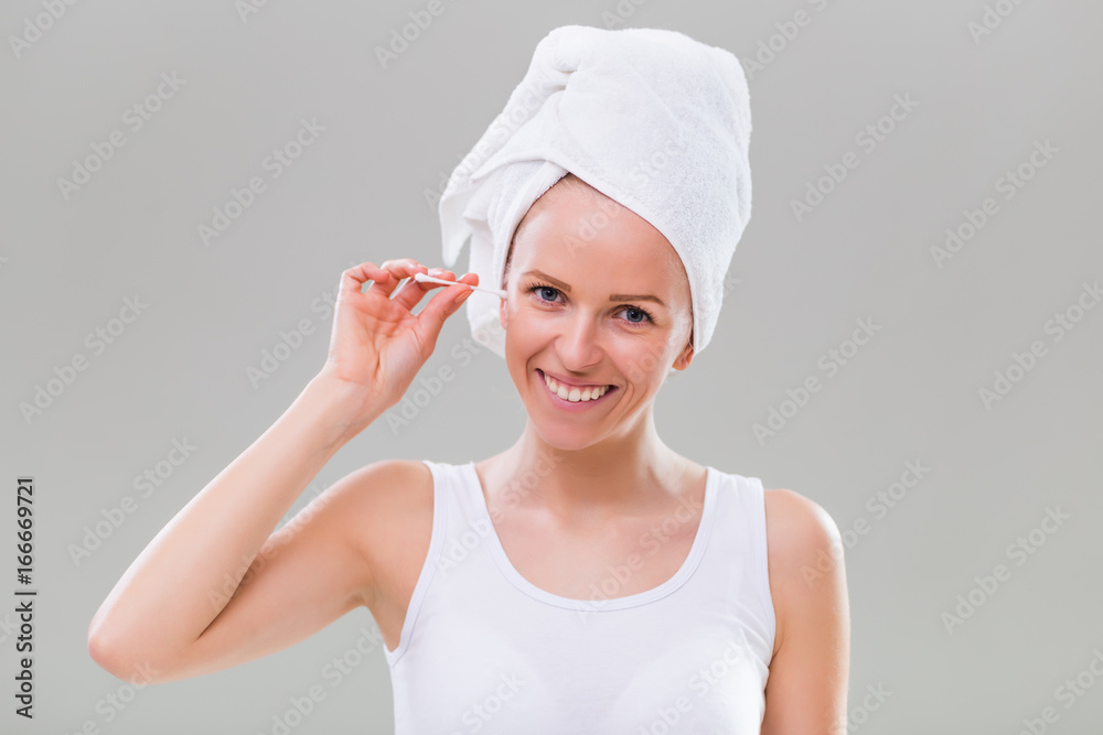 Beautiful young woman cleaning ears on gray background. Beautiful young woman cleaning ears on gray background.