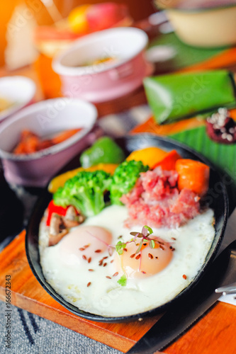 Breakfast - Fried eggs with sausages, fermented pork and vegetable served with fruits