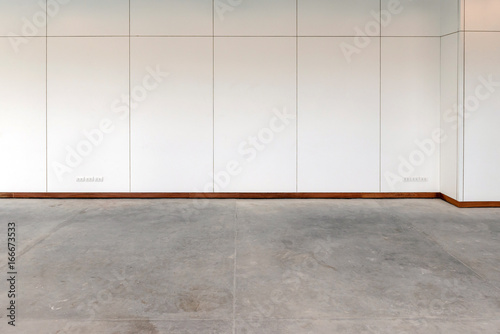 Empty room with concrete flooring and white wooden laminate wall © bigy9950