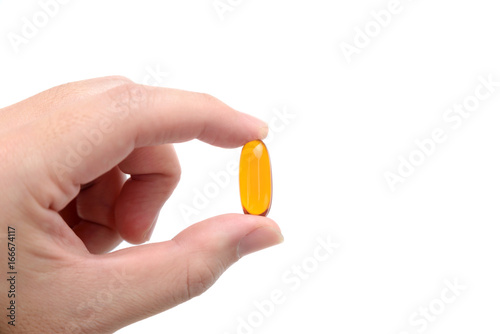 Close up to fish oil capsule in fingers on white background