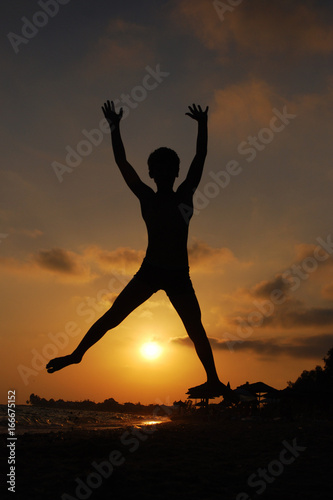 Boy jumping on beach at sunset. Happy Child on the sea. Summer vacation concept