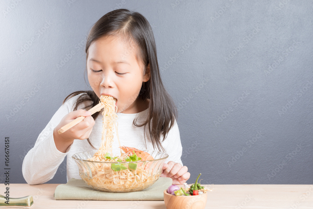 Happy Asian child eating delicious noodle Happy Asian child eating delicious noodle