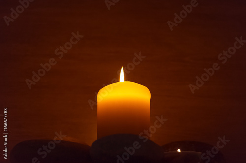 A candle is lit and surrounded by stones.