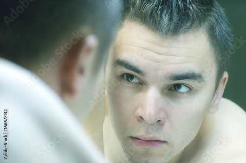 The young man looks at himself in the mirror
