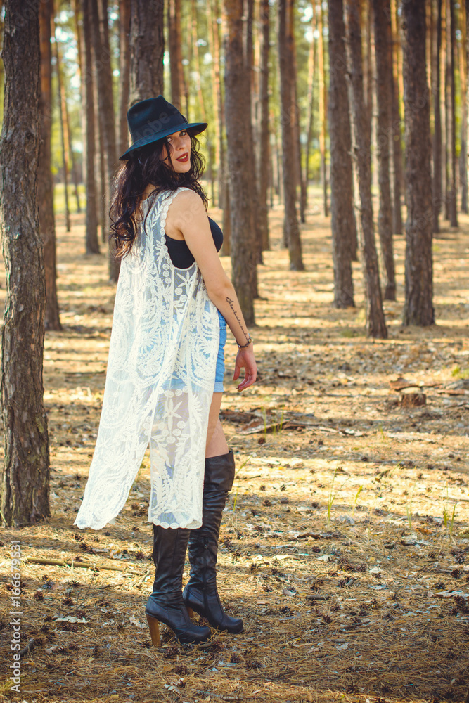 Stylish brunette woman walk into forest have a grace and charisma. Young lady in fedora black hat and interesting accessorize Stylish brunette woman walk into forest have a grace and charisma. Young lady in fedora black hat and interesting accessorize
