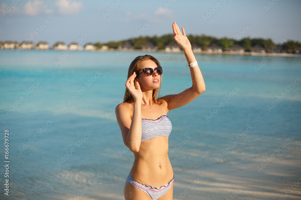 Spa wellness beach beauty woman in bikini swimwear relaxing and sun bathing  near blue lagoon. Beautiful peaceful young female model on holiday travel  tropical resort. Sun tan cream protection concept foto de