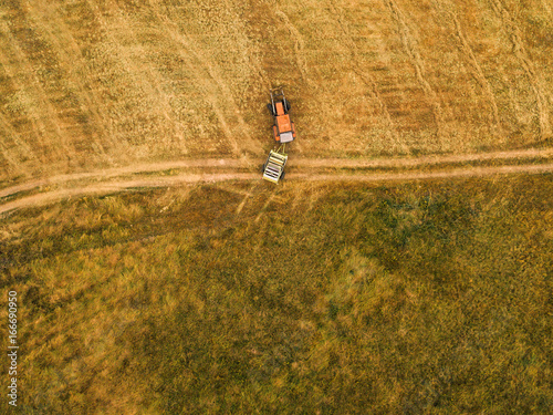 Aerial view of tractor making hay bale rolls in field