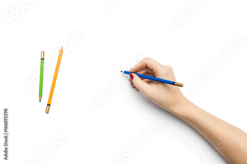 White tabletop scene with female hand writing on a blank paper with a pencil
