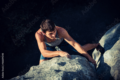 Men climbs a rock and makes hard move