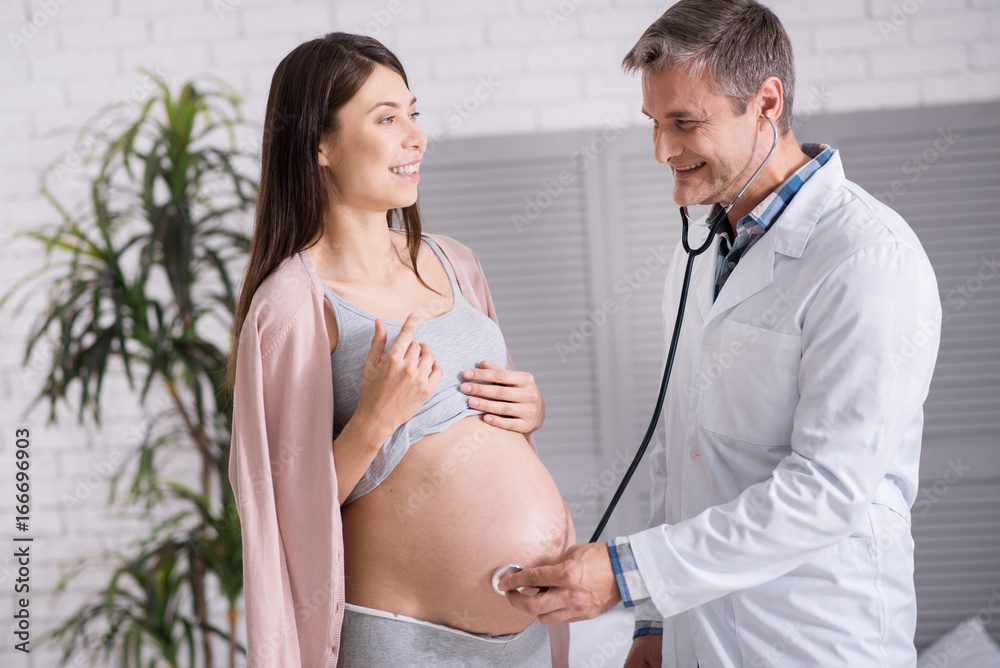 Positive delighted medical worker using stethoscope Positive delighted medical worker using stethoscope