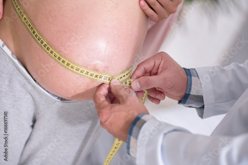 Close up of pregnant woman that measuring her bump