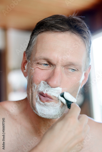 Handsome man shaving his beard.