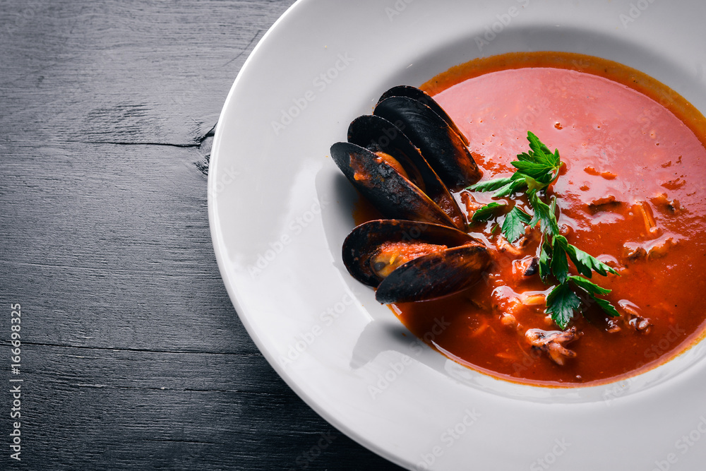 Mussels and tiger prawns in tomato sauce. Italian traditional food. On a wooden background. Top view. Free space for your text.