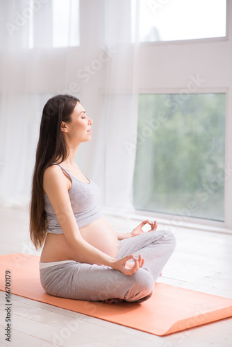 Delighted young pregnant female while meditating