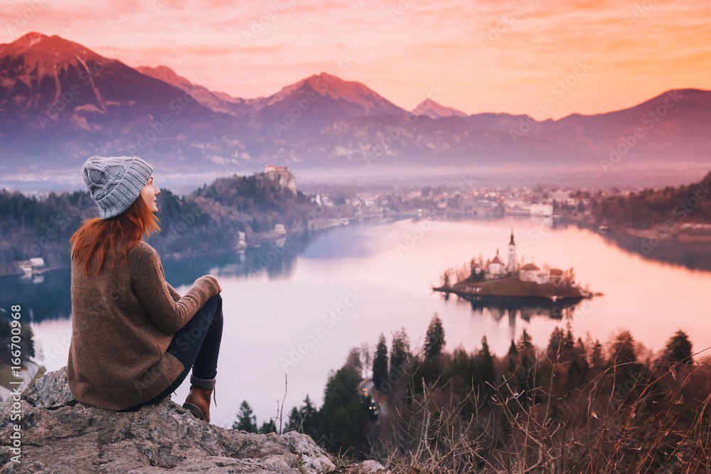 Traveling young woman looking on sunset on Bled Lake, Slovenia, Europe