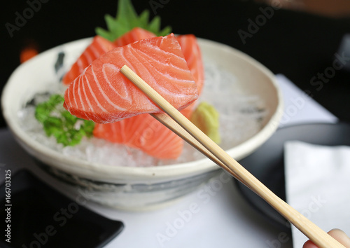 Delicious sashimi salmon on chopstick.