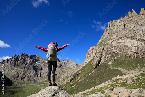 cheering woman with backpack hiking in mountains travel lifestyle success concept