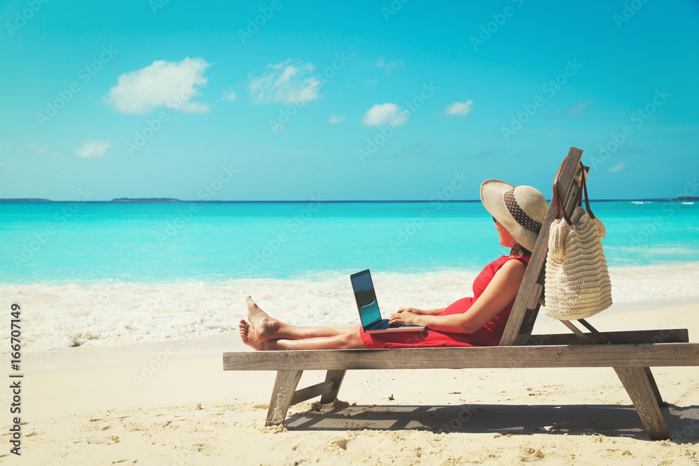 young woman with laptop on beach