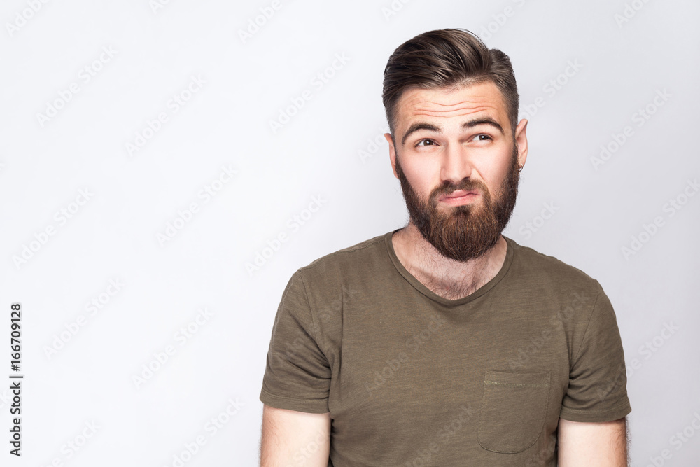 Portrait of thoughtful bearded man with dark green t shirt against light gray background. studio shot. . Portrait of thoughtful bearded man with dark green t shirt against light gray background. studio shot. .