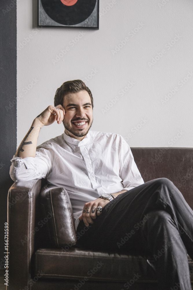 Young businessman sitting on sofa and smiling Young businessman sitting on sofa and smiling