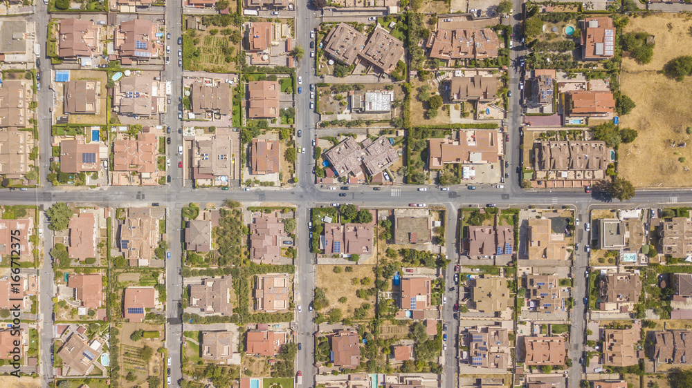 Vista aerea ortogonale di una parte del quartiere Marco Simone nella periferia nord a Roma. Tra le strade strette, le ville e i palazzi si vedono alberi. Sugli edifici ci sono antenne e parabole.