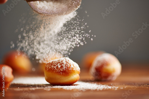 Pouring icing sugar on donut holes photo