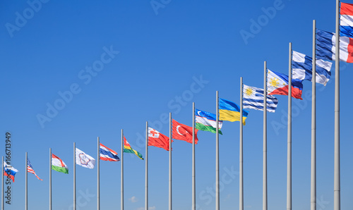 Flags of many countries flutter on the background of the blue sky in sunny day