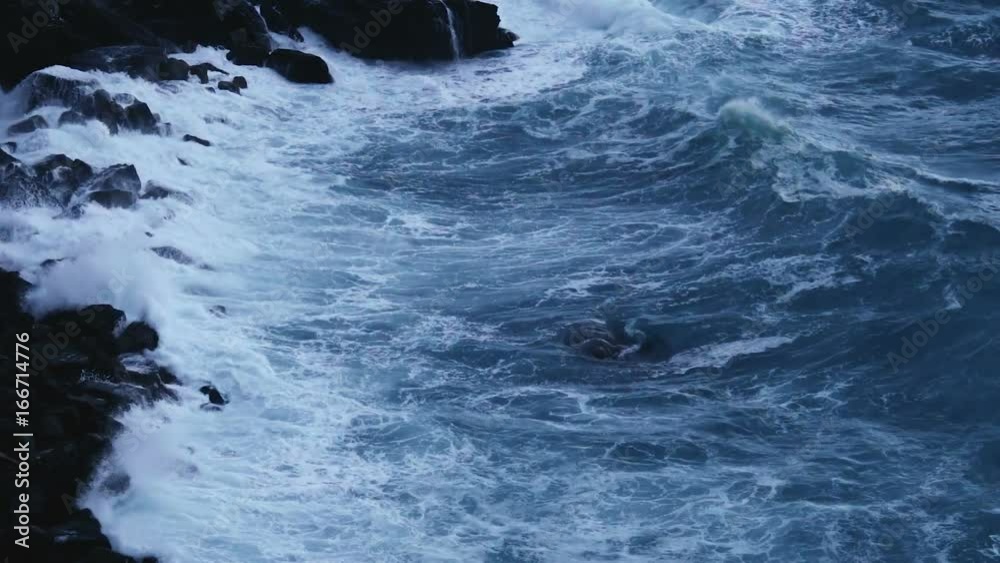 Deep blue sea waves splashing and crashing into cliff stones, stormy weather Deep blue sea waves splashing and crashing into cliff stones, stormy weather