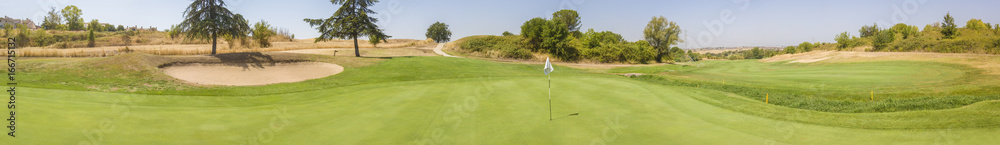 Ampia vista panoramica sulla buca finale di un circolo da golf molto grande e ricco di verde. Ci sono ostacoli sabbiosi e alberi in modo da complicare il gioco agli sportivi. Ampia vista panoramica sulla buca finale di un circolo da golf molto grande e ricco di verde. Ci sono ostacoli sabbiosi e alberi in modo da complicare il gioco agli sportivi.