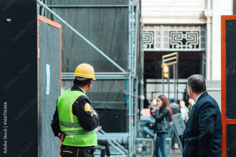 Two security men standing at the entrance of a construction site Two security men standing at the entrance of a construction site
